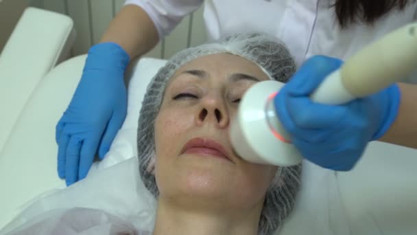 Лікар проводить омолодження обличчя жінки — стокове відео