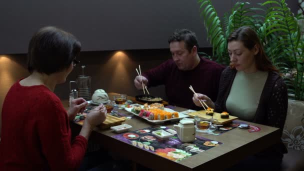 Three people eating sushi and rolls — Stock Video
