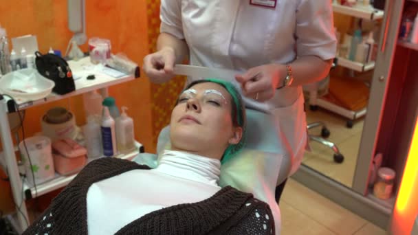 Kosmetikerin legt Film auf Augenbrauen — Stockvideo