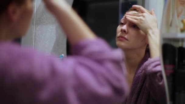 Una mujer obtiene una crema hidratante en su cara — Vídeos de Stock