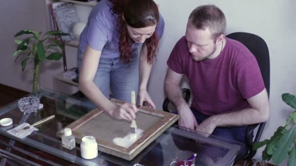 Hombre y mujer se aplican imprimación sobre lienzo — Vídeos de Stock