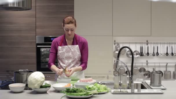 A woman cleans the kitchen knife onion — Stock Video