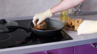 Cook Balık biftek tavaya koyar.