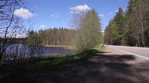 Człowiek, jazda na rowerze przez Road, w pobliżu jeziora — Wideo stockowe