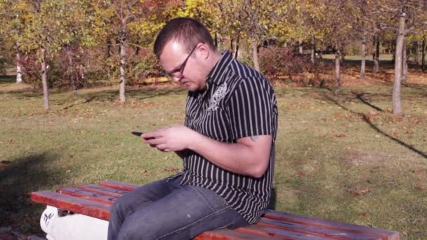 Ο άνθρωπος χρησιμοποιώντας Smartphone στο πάρκο φθινόπωρο — Αρχείο Βίντεο