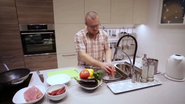 Hombre lavando verduras en la cocina — Vídeo de stock