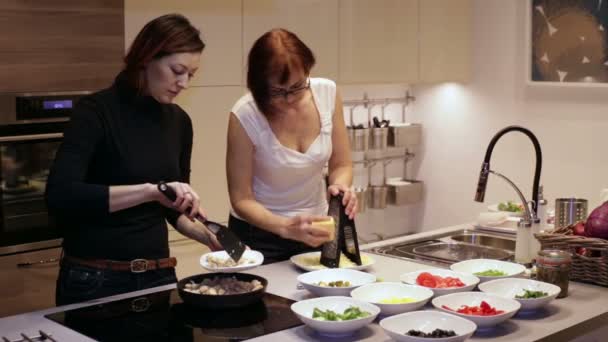 Mãe e filha cozinhar alimentos em uma cozinha — Vídeo de Stock