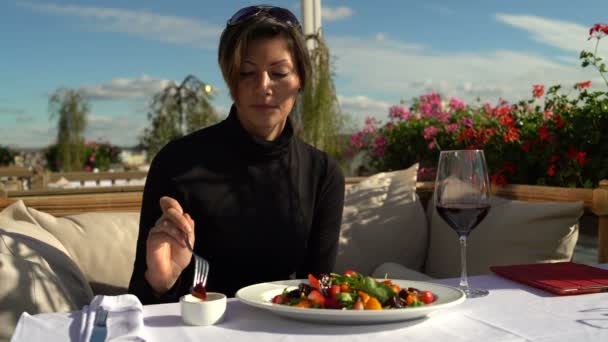 Mujer come una deliciosa ensalada en el restaurante en la terraza — Vídeos de Stock