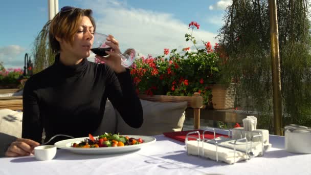 Mujer bebiendo una copa de vino tinto en la terraza del restaurante — Vídeos de Stock