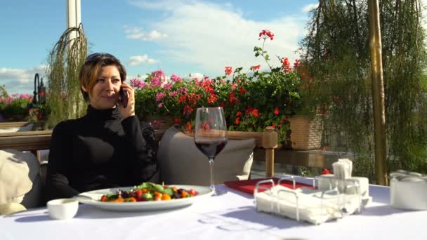Mujer hablando en el Smartphone en la hermosa terraza del restaurante — Vídeos de Stock