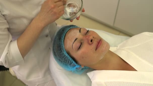Косметолог намазал лицо женщины кремом — стоковое видео