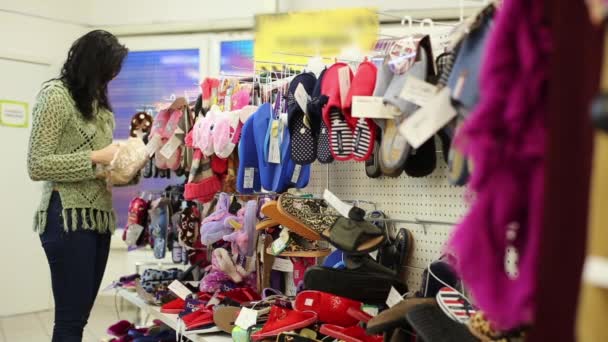 Mujer elige zapatillas en una tienda de ropa — Vídeo de stock