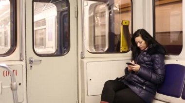 Kadın bir metro arabada bir akıllı telefon kullanır