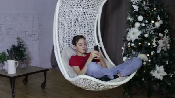 Niño usando un teléfono inteligente, fondo de Navidad — Vídeos de Stock