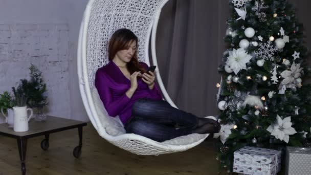 Kullanan bir akıllı telefon, Noel arka plan kadın — Stok video