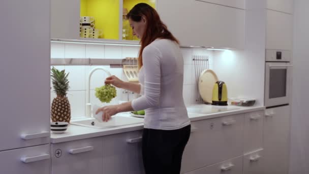 Chica lava las uvas en el fregadero de la cocina — Vídeos de Stock