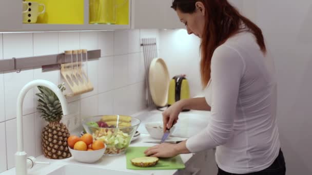 Mujer corte piña con un cuchillo en el tablero — Vídeo de stock