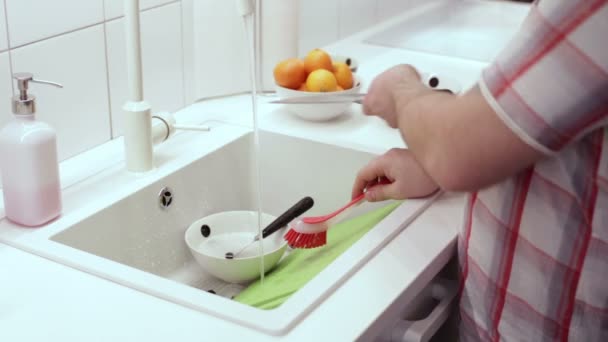 男はシンク ブラシで皿を洗っています。 — ストック動画
