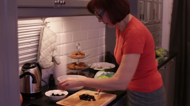 Vrouw snijdt de olijven op een houten snijplank — Stockvideo