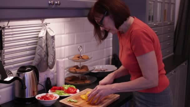 Mujer corta pimiento amarillo en una tabla de cortar de madera — Vídeos de Stock