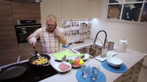 Zakenman koken en het beantwoorden van de telefoon — Stockvideo