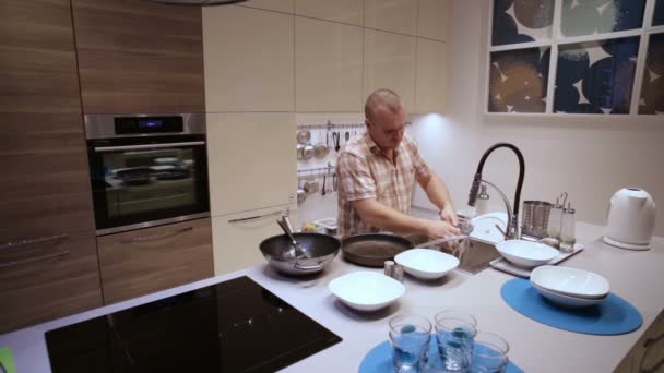Άνθρωπος που κάνει τα πιάτα μετά το δείπνο στην κουζίνα — Αρχείο Βίντεο