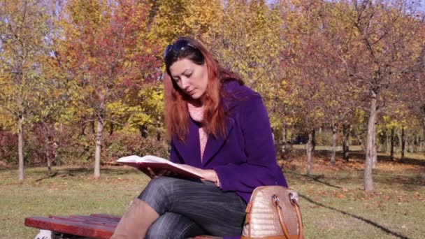 Una donna che legge un libro su una panchina del parco — Video Stock