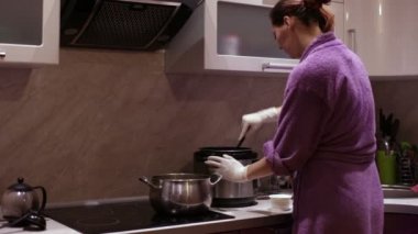 Bir kadın bir pot kıpırdanırken kaşığı baharat ekler