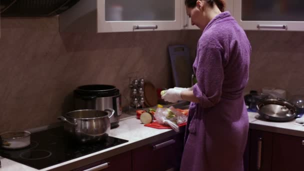 Vrouw in handschoenen reinigt courgette in de keuken — Stockvideo