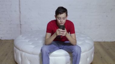 Kanepede oturan ve akıllı telefon kontrol genç