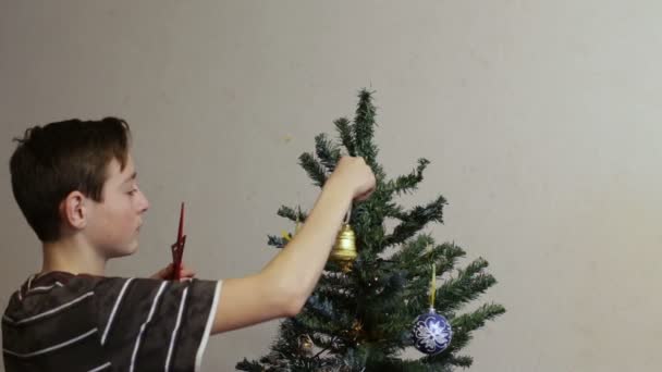 Tonåring sätter på röda stjärnan på en julgran — Stockvideo