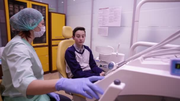 Doctor baja y inclina silla dental con paciente — Vídeo de stock