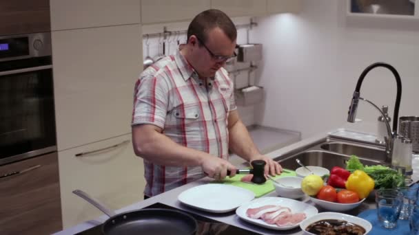 Мужчина бьет молотком свинину на кухне — стоковое видео