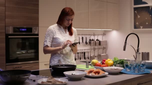 Жінка використовує смартфон на кухні — стокове відео