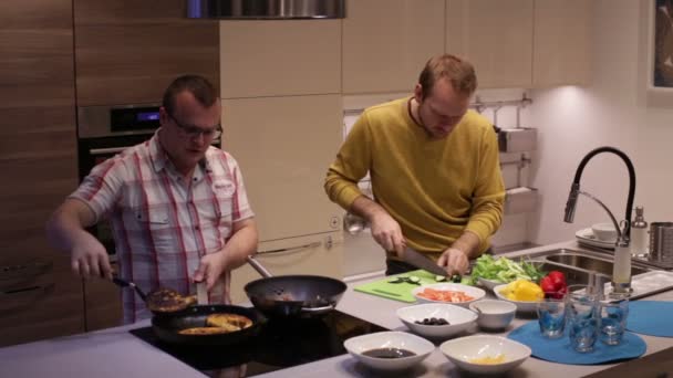 Hombres preparando comida en la cocina y hablando — Vídeo de stock