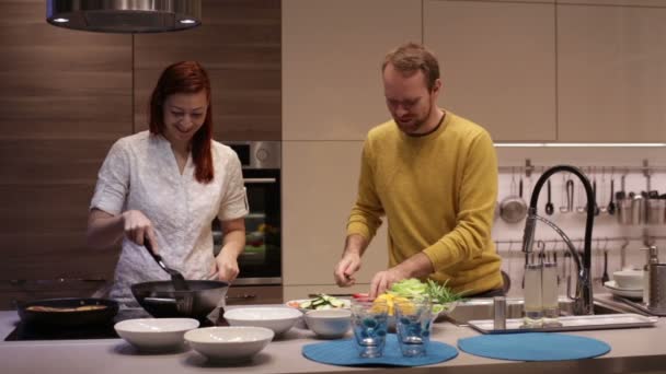 Pareja joven preparando comida en la cocina . — Vídeos de Stock