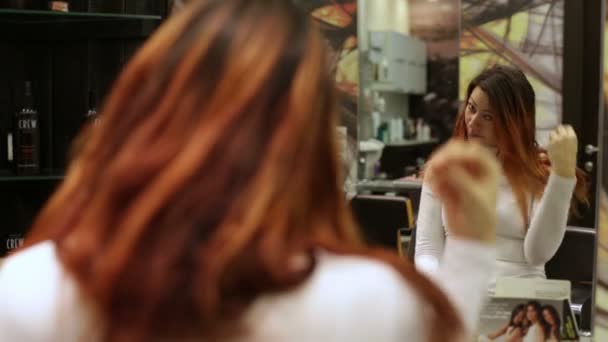 Une femme qui regarde ses cheveux dans le miroir — Video