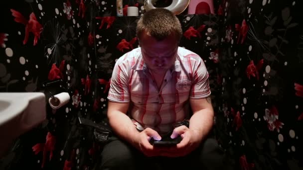 Hombre sentado en el inodoro con teléfono inteligente — Vídeo de stock