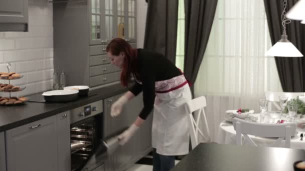 Женщина кладет блюдо с мясом в духовку — стоковое видео