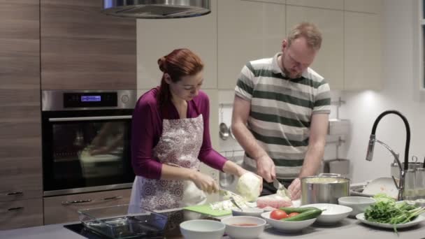 Молодая пара режет овощи на кухне — стоковое видео