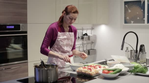 Frau in Küche gießt Essenssoße ein — Stockvideo