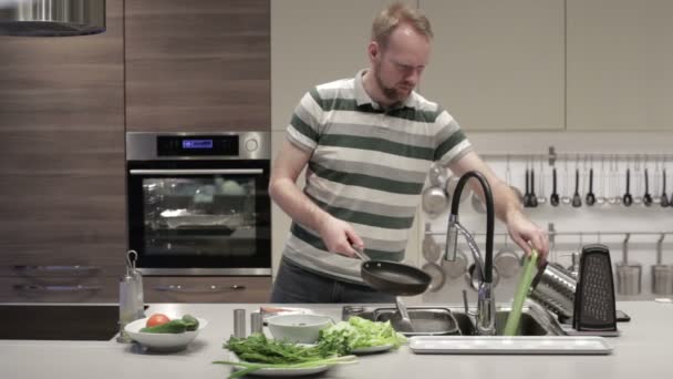 Un homme lave une casserole et met une assiette — Video