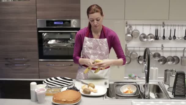 Uma mulher limpa a banana da cozinha — Vídeo de Stock