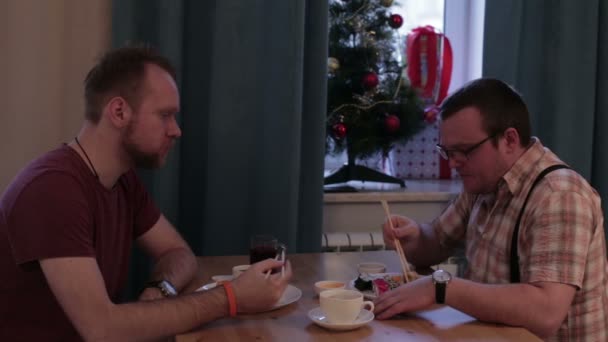 Двое мужчин сидят за столом и едят суши. — стоковое видео