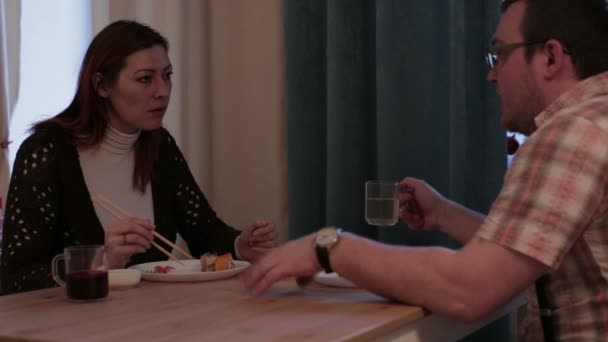 Σύζυγος και η σύζυγος κάθεται στο τραπέζι, τρώει σούσι — Αρχείο Βίντεο