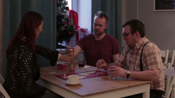 Amigos juegan un juego de mesa sentado a la mesa — Vídeo de stock