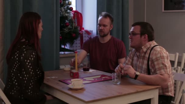 Άνθρωποι παίζουν ένα επιτραπέζιο παιχνίδι που κάθεται στο τραπέζι — Αρχείο Βίντεο