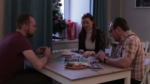 Mujer y dos hombres jugando un juego de mesa con cartas — Vídeo de stock