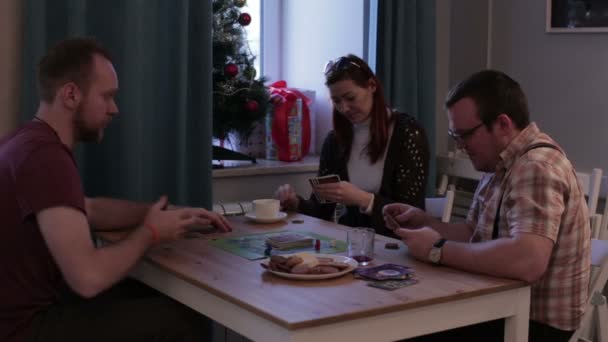 Two men and woman playing a board game with cards — Stock Video