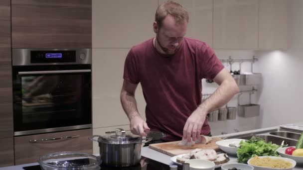 Man i köket skär fisken i biffar — Stockvideo